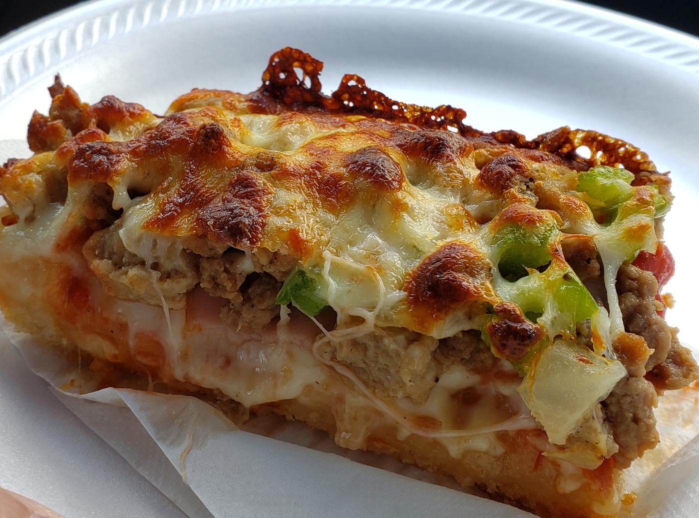 A thick, loaded slice of Pizza Glen pizza with a crisp lacy cheese edge