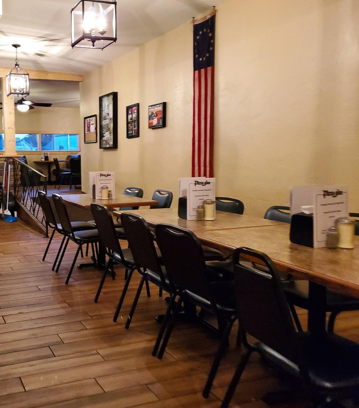 The Pizza Glen dining room: wood floors, long tables and a flag on the wall